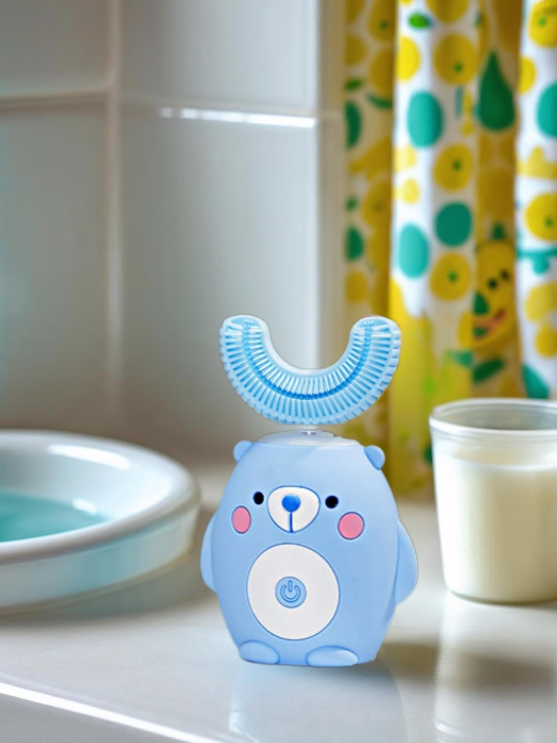 Blue bear-shaped toothbrush on a bathroom counter with a colorful shower curtain in the background.