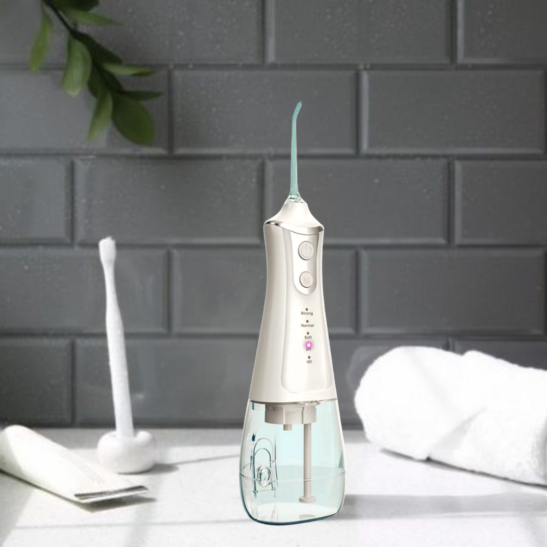 White dental water flosser on a bathroom counter with a gray tiled wall in the background.